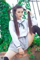 A woman in a school uniform sitting on a brick wall.