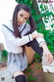 A woman in a school uniform sitting on a brick wall.