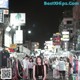 A woman standing in the middle of a crowded street at night.