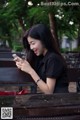 A woman sitting on a bench looking at her phone.