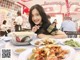 A woman sitting at a table with plates of food.