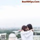 A couple of women standing next to each other on top of a building.