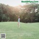 A woman walking across a lush green field.