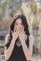 A woman in a black dress covering her face with her hands.