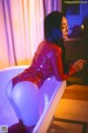 A woman in a red latex outfit sitting in a bathtub.