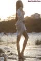 A woman in a white dress standing in the water.