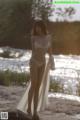 A woman in a white lingerie standing on a beach.