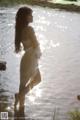 A woman in a white dress standing in the water.