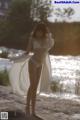 A woman in a white lingerie standing on a beach.