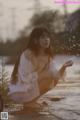 A woman in a white dress crouching down in the water.