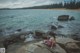 A woman sitting on a rock by the ocean.