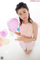 A young girl holding a bunch of balloons in her hand.