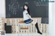 A woman sitting on a chair in front of a blackboard.