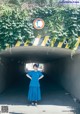 A woman in a blue dress standing in a tunnel.