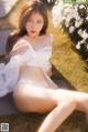 A woman in a white lingerie sitting on a bench.