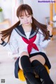 A woman in a school uniform sitting on a chair.