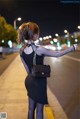 A woman in a black dress is walking down the street.