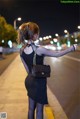 A woman in a black dress is walking down the street.