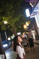 A woman standing in the middle of a city at night.