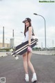 A woman holding a skateboard on the side of a road.